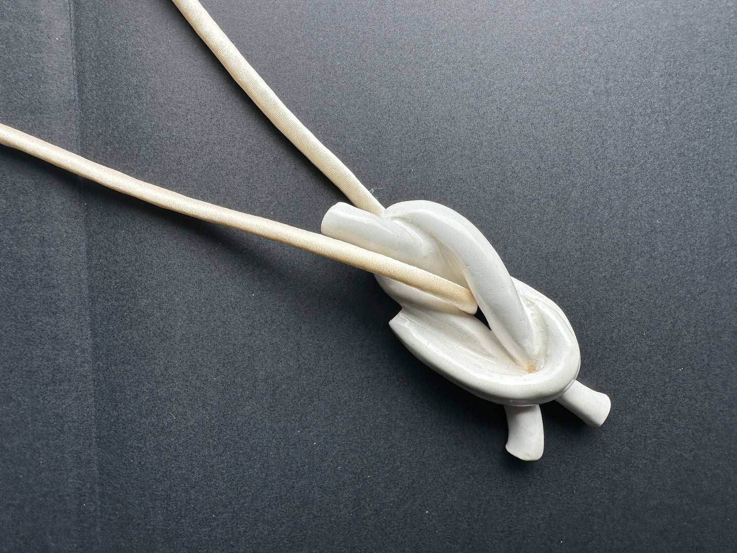 Ceramic knot pendant with ivory silk cord